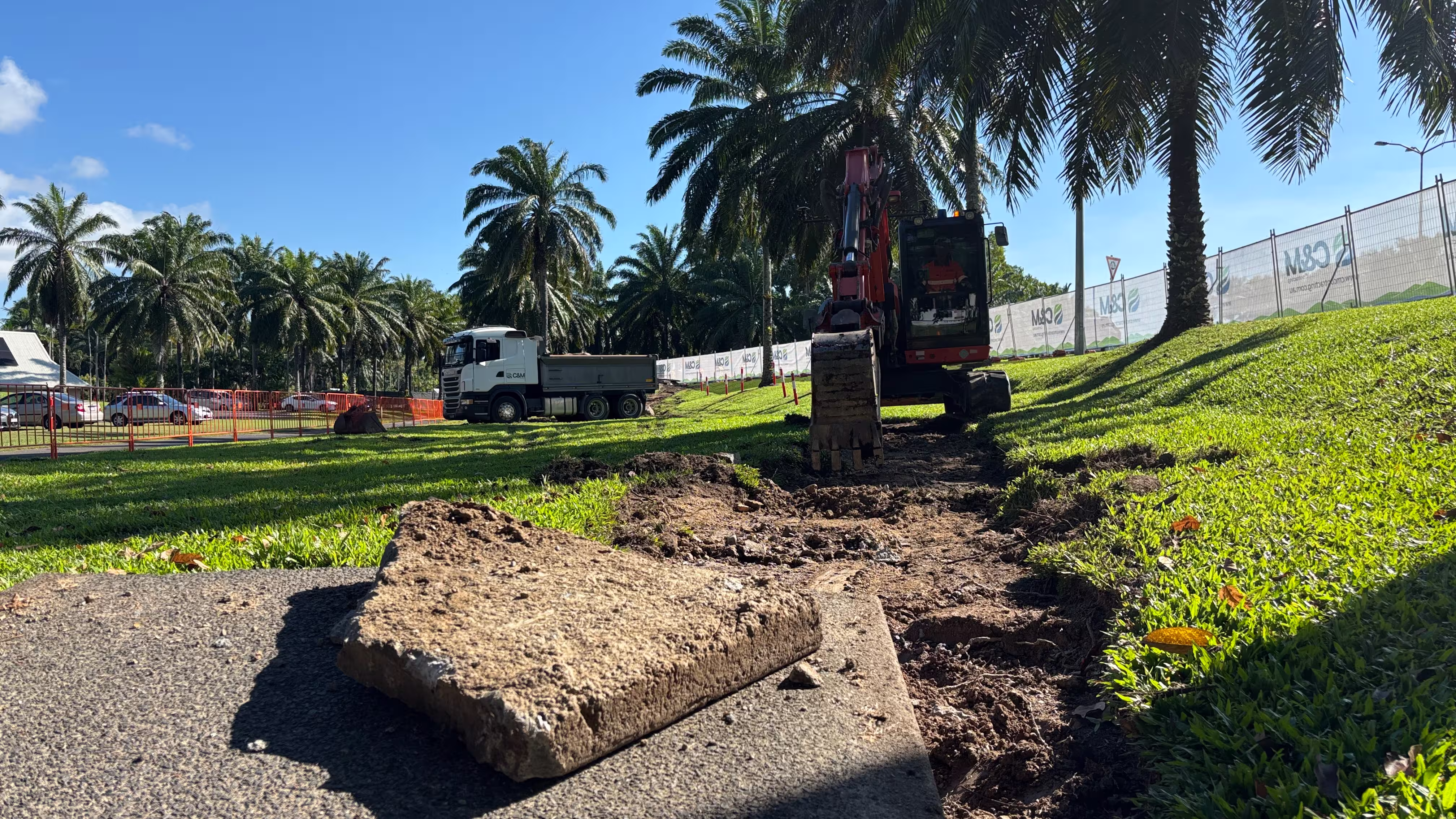 Ground preparation and works in progress at Port Douglas footpath upgrade with orange safety barriers